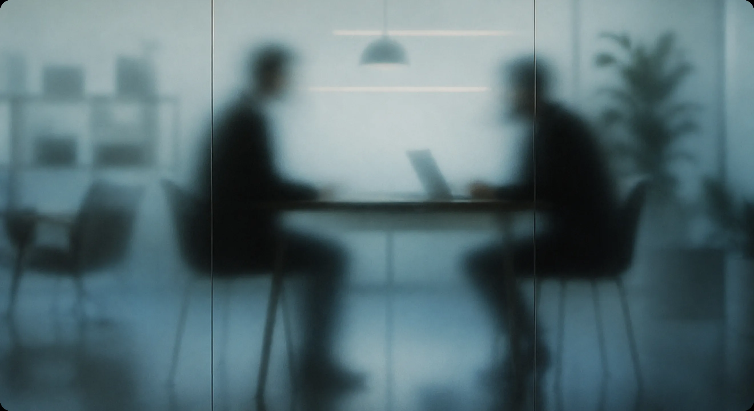 Two people in a meeting behind frosted glass